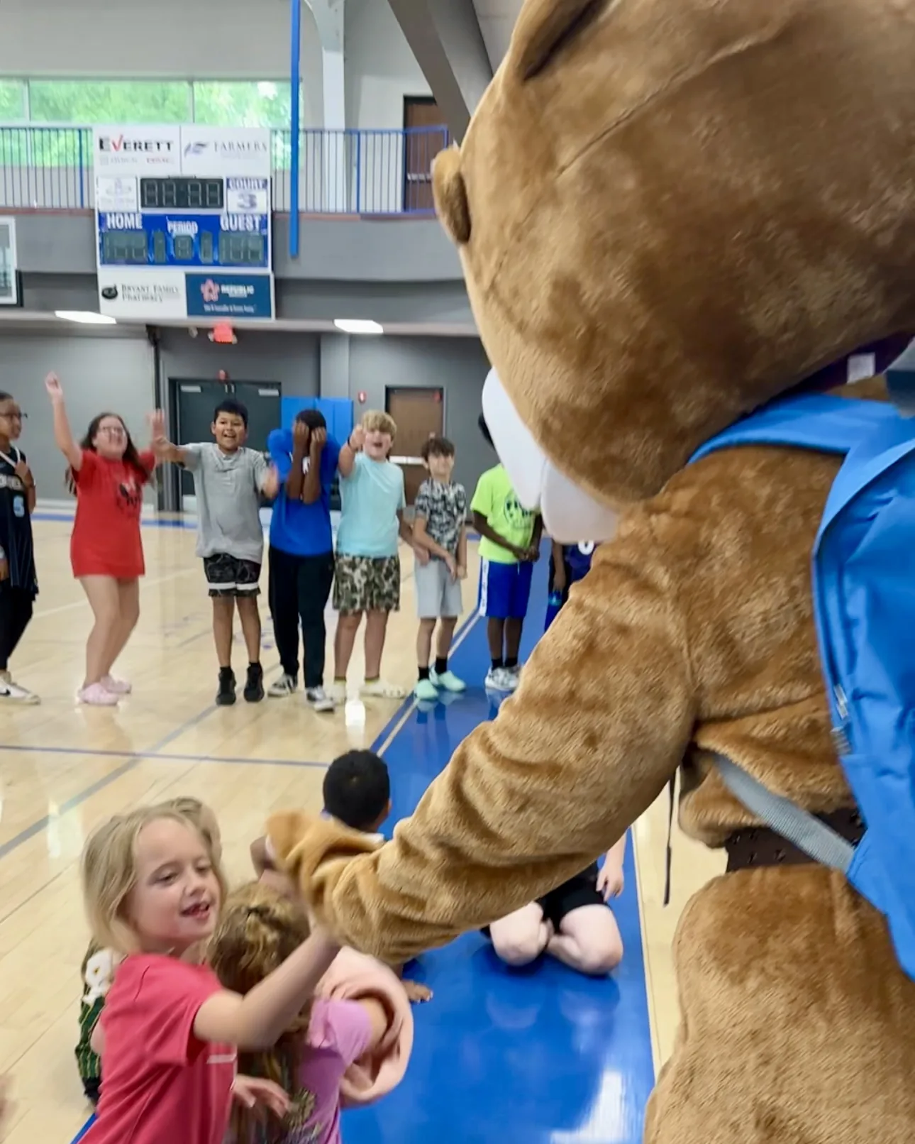 Champ the bear mascot giving a high-five to a girl in the Bryant Youth Association gym in Bryant, AR