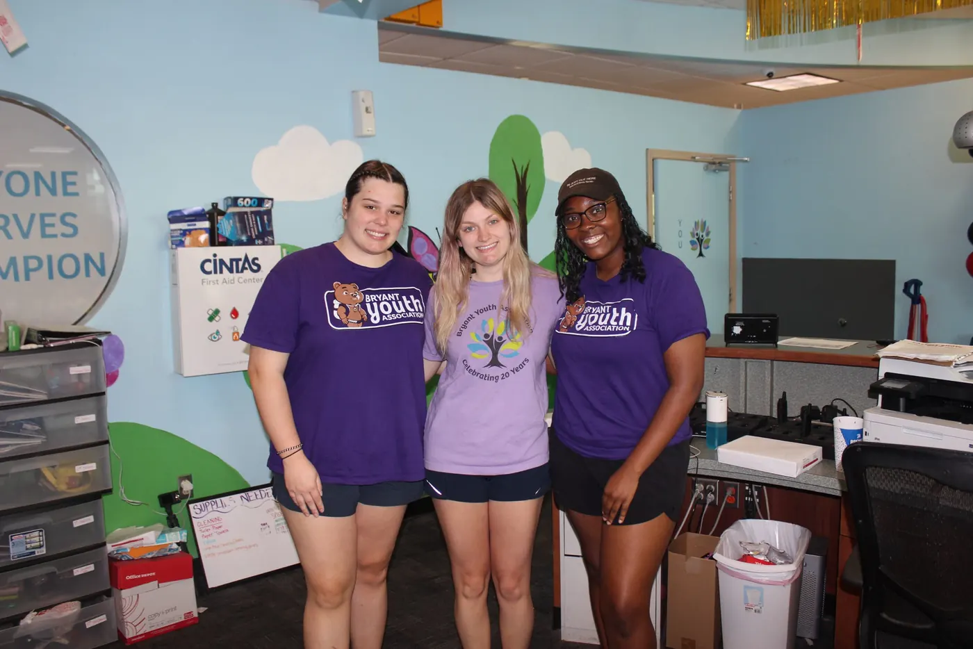 Three Bryant Youth Association program staff members in BYA shirts at the office in Bryant, AR