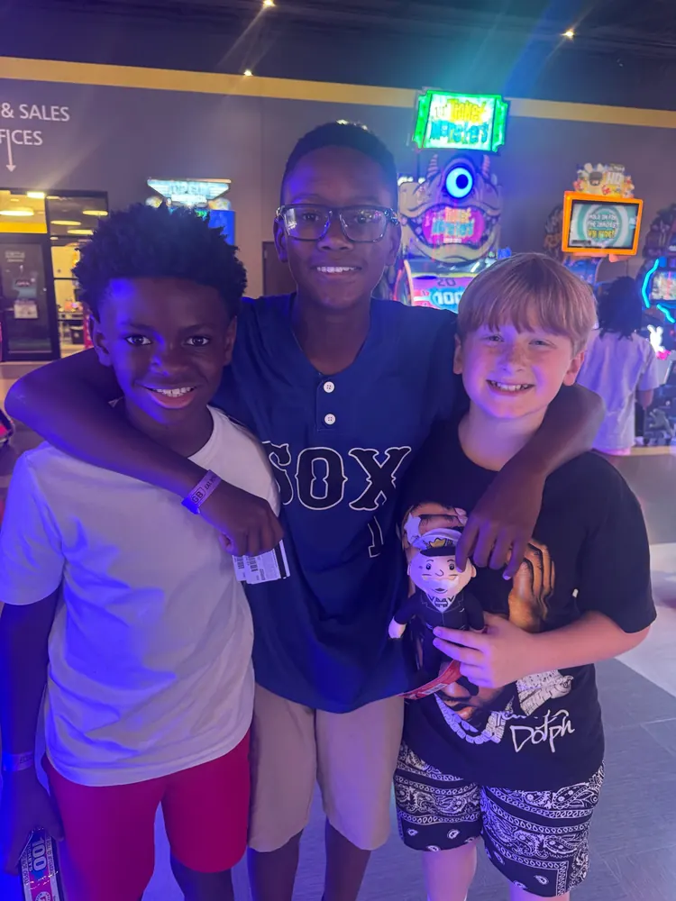 Three friends hugging and smiling on a Bryant Youth Association outing from Bryant, AR